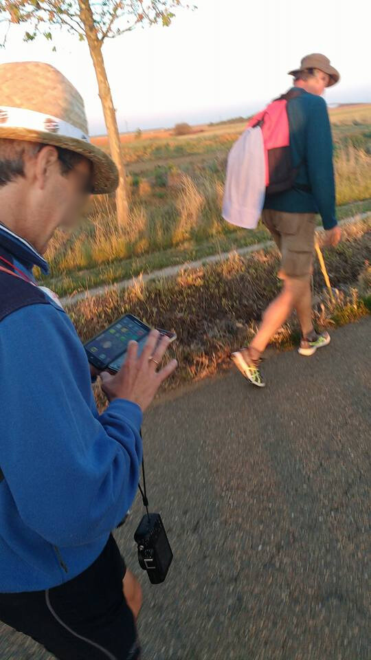 Man in a hat walking and texting on a Smartphone